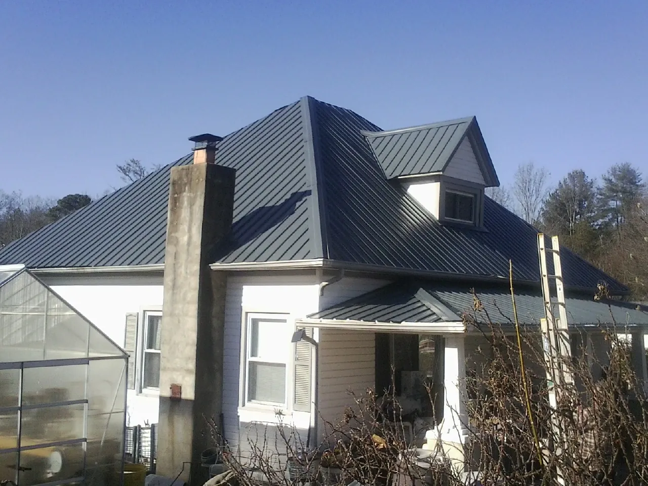 Dark blue standing seam metal roof on a white farmhouse with dormer — Slate & Tile Roof Repair by Roofing Brothers in Ellendale