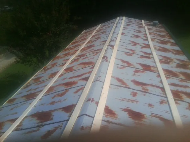 Rusted metal roof panels with new wood purlins before replacement — Storm Damage Roof Repair in Ellendale by Roofing Brothers