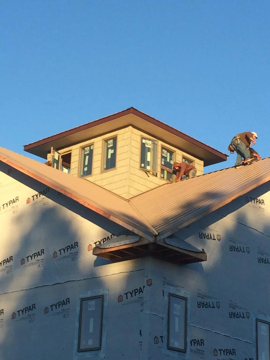 Roofers working around a rooftop cupola on a new metal roof at sunset — Roof Waterproofing in Ellendale by Roofing Brothers
